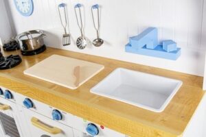 Leomark Cucina Saint Tropez in legno bianco blu, cucina con accessori, orologio, forno, lavatrice e lavastoviglie + 4 quattro casse di legno con generi alimentari, Dimensioni: 106x32x107 cm.